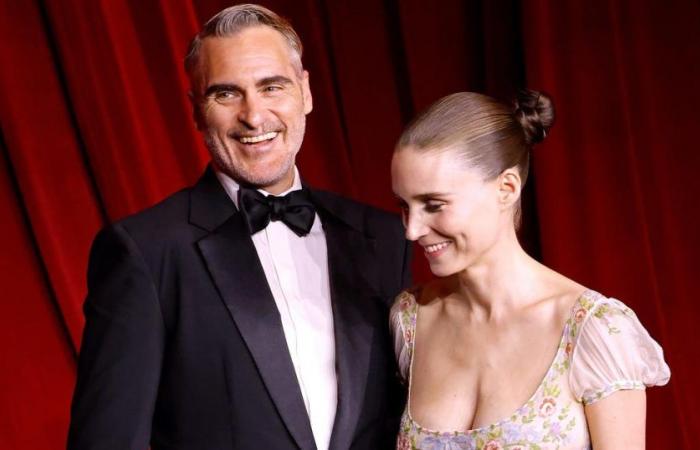 Da perfetto gentiluomo, Joaquin Phoenix aggiusta l’abito della sua compagna, Rooney Mara, sul red carpet di Los Angeles